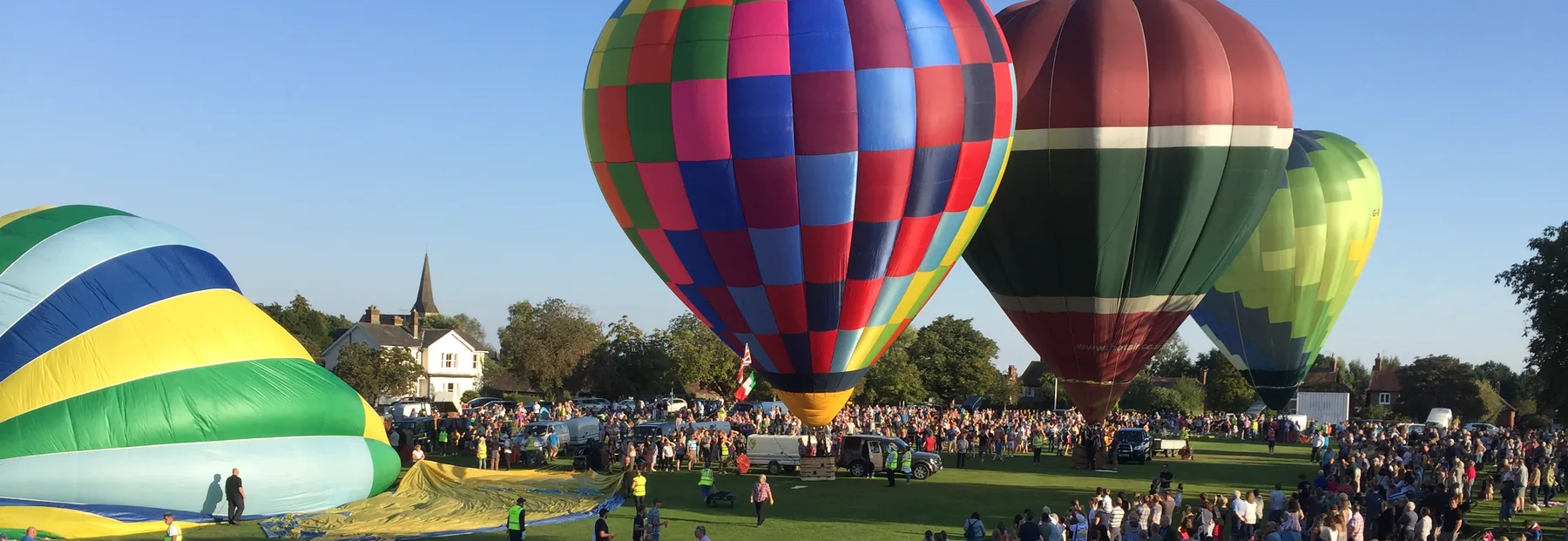 Hot-air balloons inflating on the Village Green in front of a large crowd
