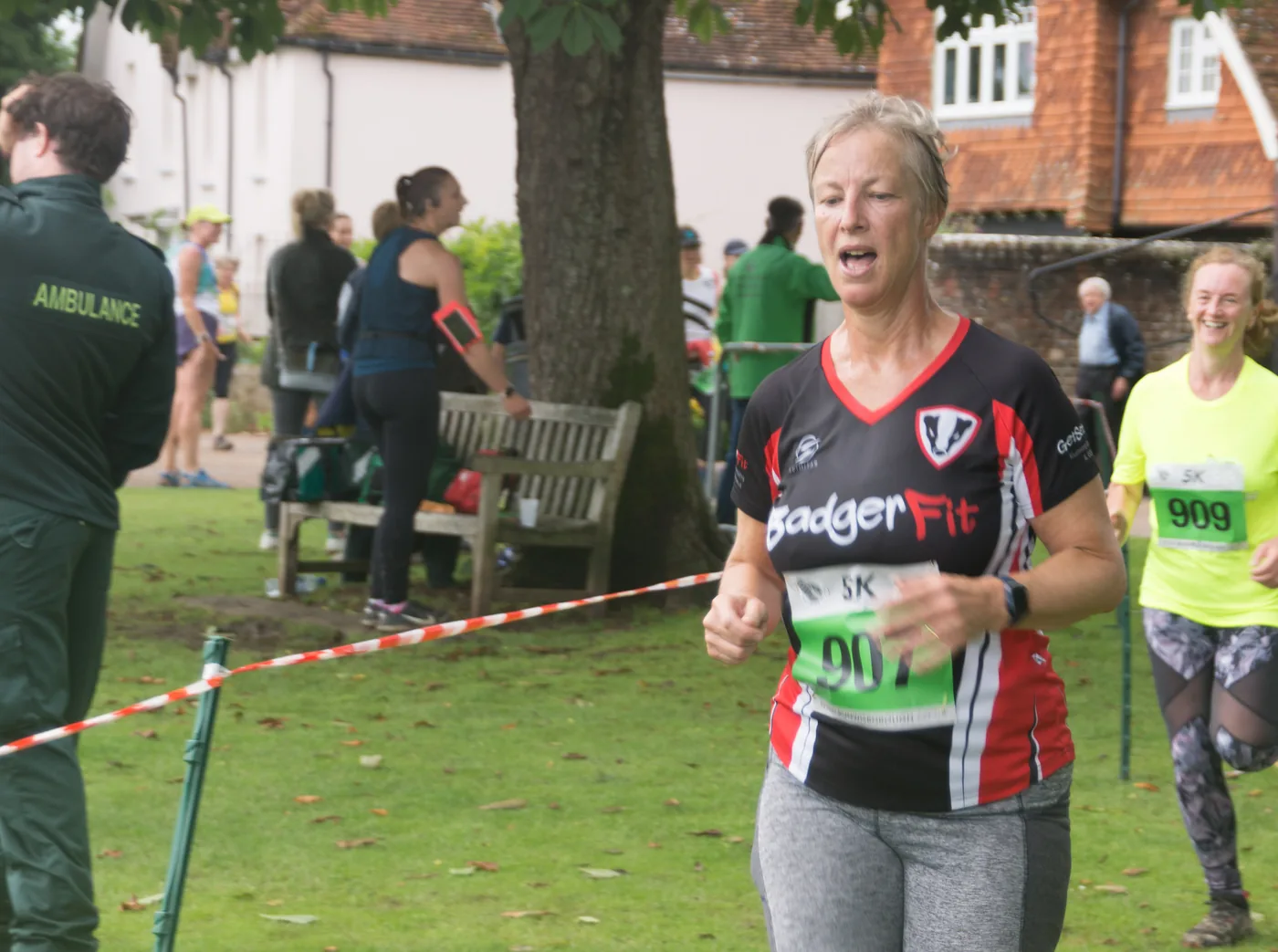 A runner in BadgerFit colours coming down the finishing straight, with another close behind