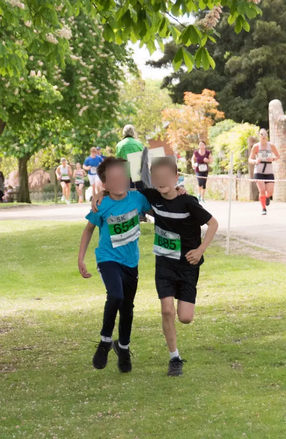 Two young runners finishing RunWisborough arm in arm